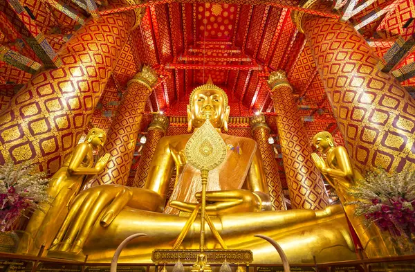 Ayutthaya, Tayland 'daki Phanan Choeng tapınağının içinde kırmızı ve altın süslerle süslenmiş büyük altın bir Buda heykeli.