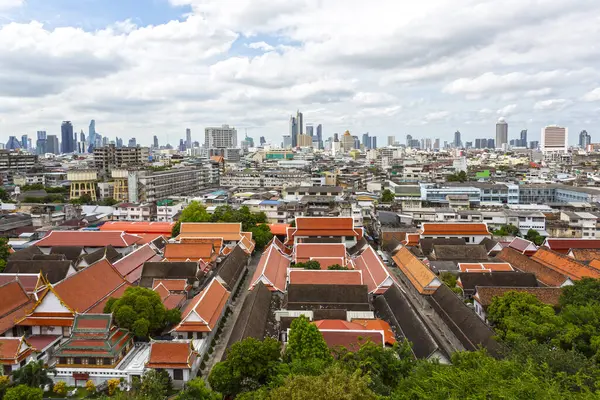 Bangkok, Tayland 'ın panoramik manzarası, geleneksel kırmızı çatılı binalar ve modern gökyüzü çizgisi karışımını sergiliyor.