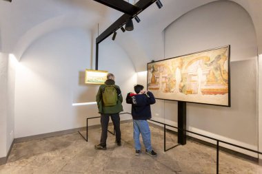 NAPLES, ITALY, Mart 01, 2025: İki kişi, bir yetişkin ve bir çocuk, modern bir sanat galerisinde sergilenen tabloları beyaz duvarlar ve ray aydınlatma