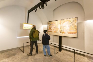 NAPLES, ITALY, Mart 01, 2025: İki kişi, bir yetişkin ve bir çocuk, modern bir sanat galerisinde sergilenen tabloları beyaz duvarlar ve ray aydınlatma