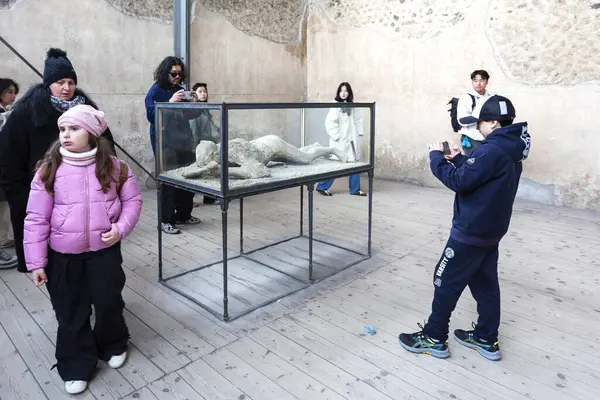 POMPEII, ITALY 2025, Mart 02: Turistler, Pompeii, İtalya 'nın arkeolojik sahasında Vesuvius Dağı' nın patlamasından korunmuş bir insan kurbanın alçısını gözlemlediler.