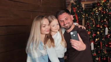 Küçük kızı olan genç bir aile uzakta yaşayan ve Noel ağacının yanında duran yaşlı ebeveynlerini tebrik ediyor. Mutlu noeller. Modern teknolojiler. Aile video çağrısı kavramı