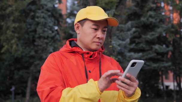 Concentrado Asiático Entregador Escreve Mensagens Texto Seu Smartphone Usar Navegação — Vídeo de Stock