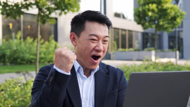 幸せな笑顔正の韓国のビジネスマン弁護士フリーランス男性投資家雇用主起業家は ラップトップの無線Lanインターネット屋外を使用して株式市場でお金を獲得オンラインプロジェクトと笑顔の成功 — ストック動画