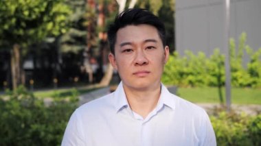 Yakışıklı odaklı Asyalı iş adamının dışarıda duran portresi iş merkezinin yakınındaki kameraya ciddi bir şekilde bakın. Başarılı kariyer çekici yönetici, başarılı insanlar.