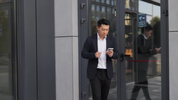 Asian Businessman Leaves Office Building Working Mobile Phone While Going — Stock Video