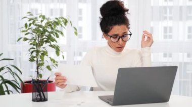 Üzgün, bitkin, üzgün, ödenmemiş bir ceza makbuzunu okuyan, banka kredisi ödemeleri hakkında stresli hisseden, ödenmemiş vergileri, finansal sorunları, para iflasını düşünen üzgün bir kız.
