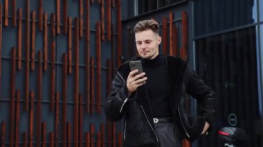 Kapalı çekim neşeli çıkış yapan iş adamı telefonda iyi haberleri ağır çekimde okuyor. Coşkulu adam online başarı kutluyor, akıllı telefon kullanarak harika haberler okuyor, şaşkına dönüyor. Zaferi kutlarken şaşırdım.