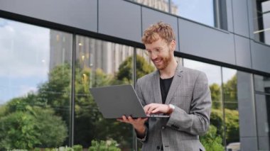 Uzaktan kumandalı gözlüklü profesyonel girişimci bilgisayarlı bilgisayarlı dizüstü bilgisayarlı daktilo kodu çevrimiçi sohbet programcısı uygulaması ofis binasının yanında duruyor.