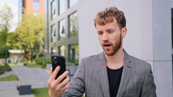 成功的商人男性自由职业者使用手机在户外进行视频通话 男性高加索人利用接近现代建筑背景的新技术在网上聊天 — 图库视频影像