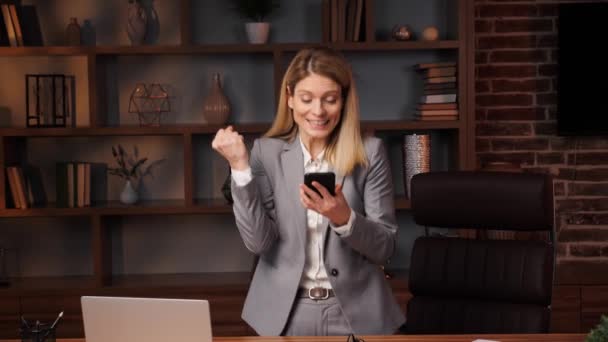 幸せなビジネス女性の肖像は 自宅のオフィスで携帯電話で成功をお楽しみください 楽しい女の子は電話で良いニュースを読んで閉じます アパートで電話で勝利を祝う驚くべき女性 新しい仕事のオファー — ストック動画