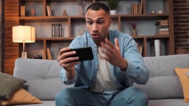 Neşeli, heyecanlı, esmer tenli adam cep telefonuyla favori futbol takımına tezahürat yapıyor. Spor bahisleri seyrediyor. Afro-amerikan erkek televizyon izliyor.