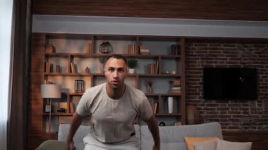 Genç Afrikalı Amerikalı adam evde spor antrenmanı yapıyor, kilo veriyor, karantina altında. Siyah tenli bir adam spor yapıyor yağ yakıyor aerobik antrenmanı yapıyor.