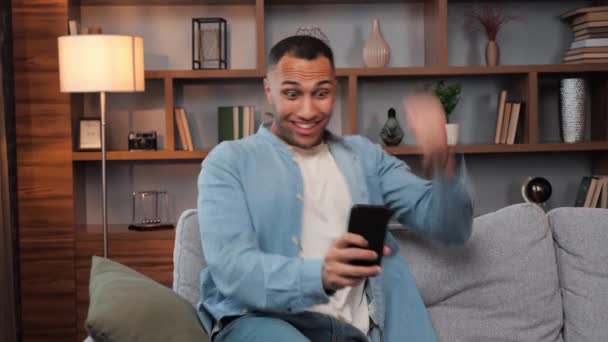 흥분한 아프리카 미국인 남자는 소파에 메시지를 미소를 짓는다 — 비디오
