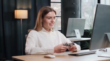 Güzel bir ofis çalışanı, elinde joystick ile iş yerinde oyun oynuyor. Heyecanlı iş kadını eğleniyor. Olumlu neşeli kız modern çatı katında iş yerinde oyunlar oynuyor.