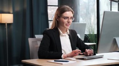 Excited pleasantly surprised beautiful business woman rejoices at the message on her pc laptop computer. Young female looking at screen and feel amazed happy and saying WOW on loft office background