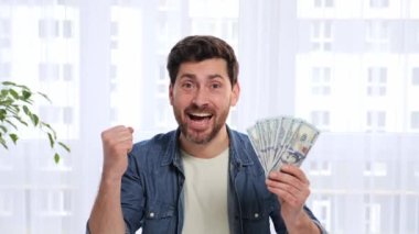 Excited and pleasantly surprised handsome man rejoices victory winning big money on sports betting game. Young male looking at web cam laptop and feel amazed happy, saying WOW on home background