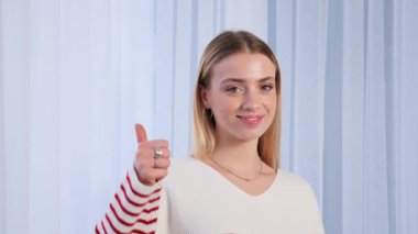 Confident happy smiling young girl teen student wears casual cool sweater showing thumb up. Satisfied woman looking at camera giving positive service or goods recommendation, approval symbol