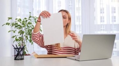 Worried woman sitting at the table reads received bad news, holds documents paper letter feels desperate about financial problems or debt, girl student reads letter of expulsion from the college