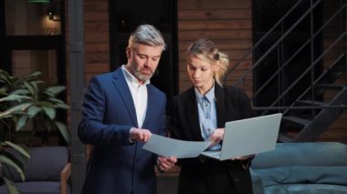 Two businessmen working on financial statistics analyzing charts project data in report, business meeting Executive analysts discussing diagrams, work with laptop, holding graphs, consulting client