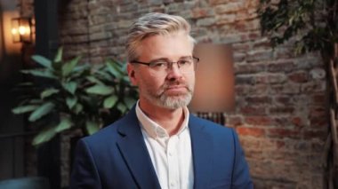 Confident handsome mature mid aged businessman in glasses, professional financial advisor, executive leader, manager, male lawyer or man entrepreneur posing for headshot, business portrait indoor