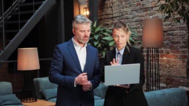 Startup investment business meeting between investor and female startupper, two diverse persons have a discussion in meeting room. Director and project manager compare business results on laptop 