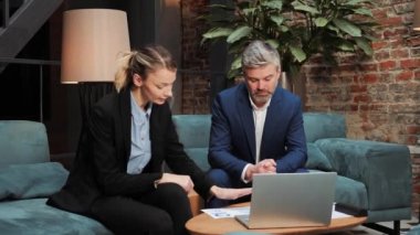 Adult confident businessman talking about plan, looking at laptop screen, discussing project. A financial advisor, a lawyer advises a bank employee on real estate investments. Businessmen meeting