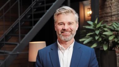 Smiling businessman looking at camera, successful man business person standing in new loft modern office in corporate building. Happy male middle age confidence professional businessman posing