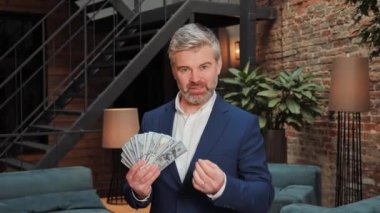 A middle-aged businessman holds a large wad of money in his hands and talks about the possibility of earning money on crypto exchanges, stock market and online casino. Easy winnings in the lottery
