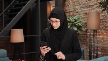 Surprised Muslim Islamic woman winner hold smartphone read good news feels euphoric amazed by mobile online bet bid game win winner, overjoyed by victory success. Financial stock sports betting