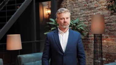 Middle age successful businessman with a beard is looking to camera while crossing hands. Financial expert, lawyer, banker leader posing in the negotiation room. Headshot business male portrait