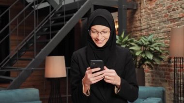 Arap Müslüman, mutlu iş kadını, gezici arayüzü kullanıyor, iyi haberler okuyor, elini kaldırıyor, evet diyor, tesettürlü kadın telefonda zafer kazanıyor. Yüz ifadesi kavramı, teknoloji