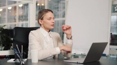 Thoughtful motivated successful businesswoman leader thinking of future corporate successful plan ideas using laptop at office desk typing on keyboard puts hand on chin dreaming in modern corporation
