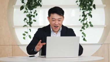 Excited Asian business man checking email reading great news on laptop Amazed male professional winner feeling happy receiving new job, bonus, celebrates financial market growth, stock sports betting