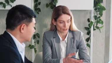 İki farklı çok uluslu iş adamı ortak konuşuyor, birlikte çalışıyor, bilgisayar kullanarak veri yönetimini tartışıyorlar. Kafkasyalı yönetici ofis toplantısında Asyalı yatırımcı istemciye danışıyor