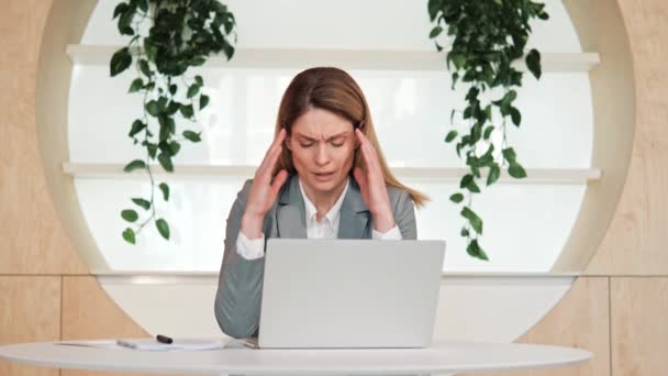 筋肉の緊張に苦しむ素敵な外観を持つストレスのある大人のビジネス女性 コンピュータの過労のために痛みを伴う頭の感情を持っています エコオフィスでの仕事に圧倒された疲れた従業員の顔 — ストック動画