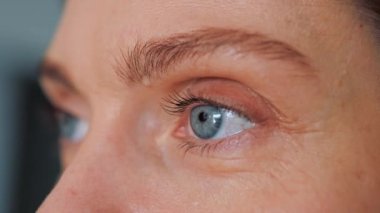 Close up of Womans face. Beautiful woman opening her beautiful blue eyes. Caucasian young adult female model with blue, green, grey eyes looking to the side. Slow-motion, macro extreme close-up