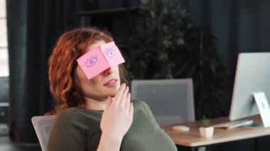 Closeup sleeping girl, funny lazy caucasian business woman tired, yawns. Sleepy female worker with sticky notes on eyes glasses with stickers sleeps in office feeling fatigued napping at workplace