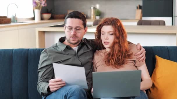 Pasangan Duduk Sofa Dengan Laptop Memegang Dokumen Membayar Tagihan Pembayaran — Stok Video