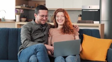 Genç Avrupalı mutlu aile portresi oturma odasındaki kanepede dinlenen bilgi arayan, bilgisayardan alışveriş yapan, hediye seçen, e-ticaret, boş zaman konsepti