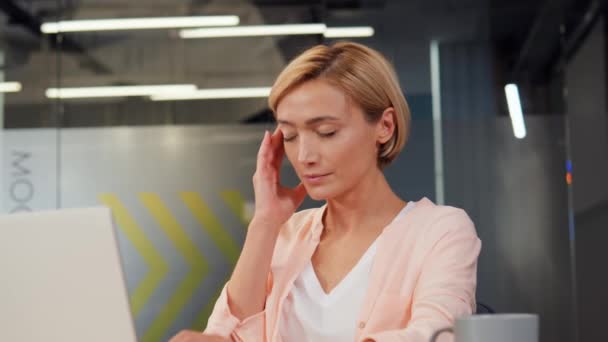 사무실에서 기진맥진 여자가 책상에서 노트북으로 일하는 두통을 경험하고 전문가들의 사회에 — 비디오