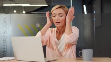 Güzel sarışın kadın modern ofis tasarımında bir ofis çalışanı, ama zayıf ses yalıtımı onu çok gürültülü yapıyor. Sonuç olarak, işiyle gelen gürültü ve dikkat dağıtıcı şeylerle boğuşuyor.