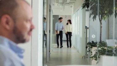 Meşgul adam ve kadın ofis koridorunda yürür ve iş fikirlerini tartışırlar. Ön planda, erkekler kadın iş arkadaşlarıyla konuşuyorlar. Takım çalışması, ofis kültürü, motivasyon hedefleri üzerinde duruldu