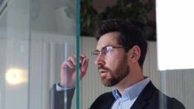 Başarılı, yorgun, fazla çalışan bir adam cam bir duvara yaklaşır, gözlüklerini çıkarır, burnunun köprüsüne masaj yapar ve yorgunluktan dolayı baş ağrısı hisseder. Ofis çalışanı işadamı acıdan muzdarip