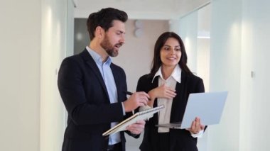 Dizüstü bilgisayarları ve defterleri olan iki işçi ofis koridorunda yeni bir projeyi tartışıyorlar. İlerlemeyi izliyorlar, teslim tarihlerini karşılamak için geri bildirim sağlıyorlar ve başarılı bir proje sağlıyorlar.