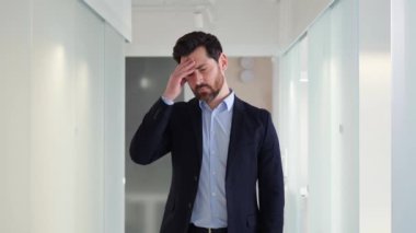 İş adamı yorgun ve şiddetli baş ağrıları çekiyor. Ezici iş talepleri hem sağlığını hem de verimliliğini olumsuz etkiledi ve yüksek basınç ortamı yarattı.