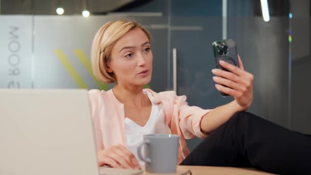 Vrolijke Blonde Kantoormedewerker Neemt Deel Aan Een Videogesprek Haar Mobiele — Stockvideo