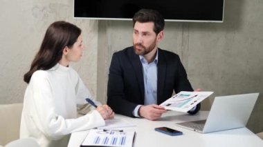 Başarılı bankacılar toplantı odasında oturmuş yatırım, kredi ve sigorta içeren bir projeyi tartışıyorlar. Elinde grafikler ve grafikler olan adam projenin büyümesi ve ilerlemesini tartışmaya odaklandı