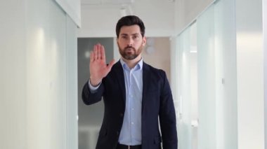 Yakışıklı adam kollarını kavuşturur ve dur der, bunu ofiste yapma. Erkek ciddi görünüyor ve muhtemelen uyarı ya da azarlama yapıyor. Uyarı mesajı veya uyulması gereken kuralların önemi