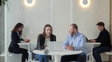 Aralarında serbest çalışanlar ve girişimcilerin de yer aldığı iş adamları bir odada birlikte çalışıyorlar. Kadın ve erkek birlikte oturuyor, dizüstü bilgisayarla proje üzerinde çalışıyorlar.